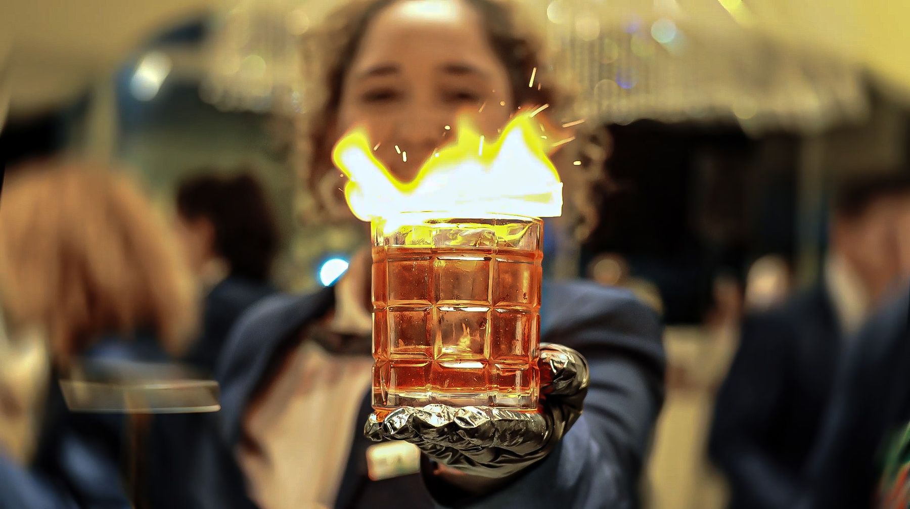 Bartender da New Fênix Drinks entregando um drink flamejante durante um evento