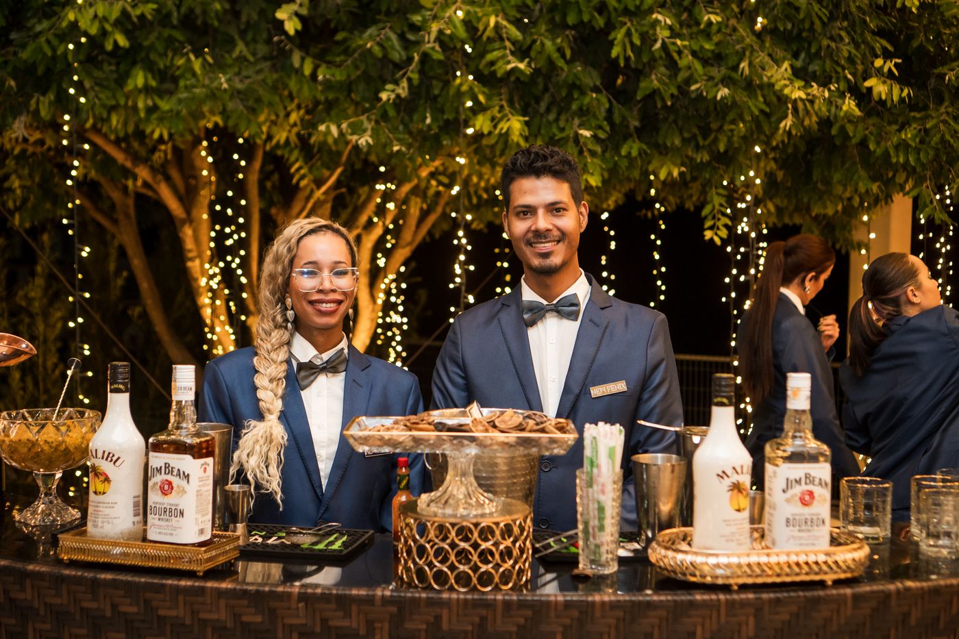 Dupla de bartenders da New Fênix Drinks atrás da bancada rústica em um evento ao ar livre