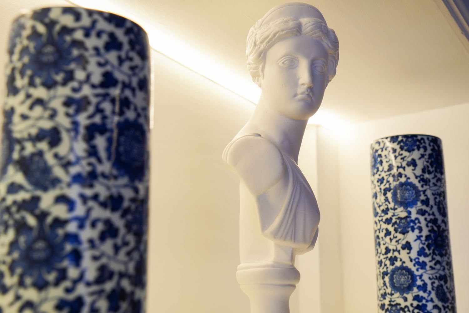 Busto grego entre vasos de porcelana no escritório