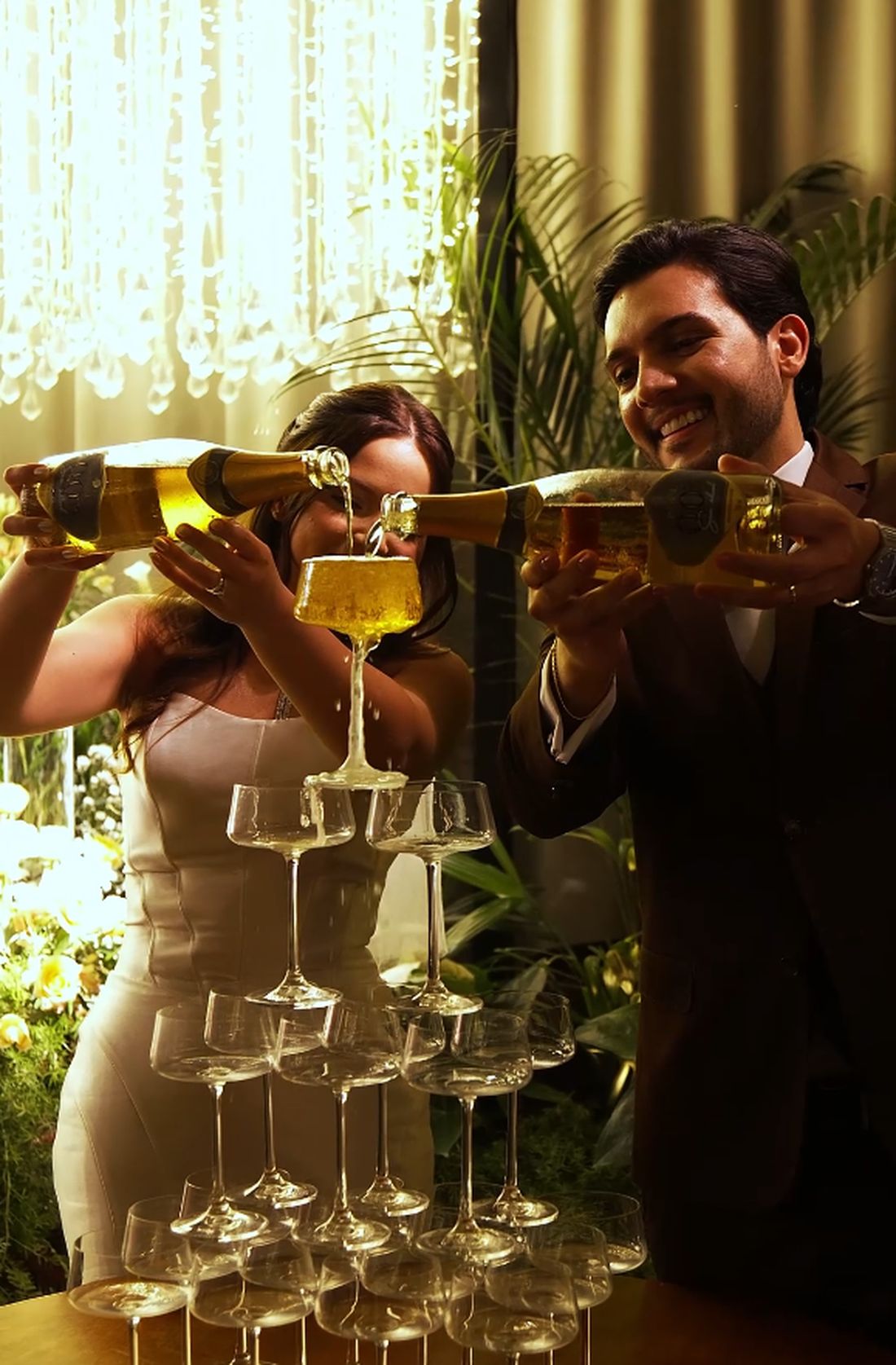 Casal servindo espumante em uma torre de taças montada pela New Fênix Drinks